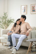 © tonefotografia - Portrait of young asian couple sitting in living room at home