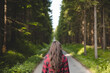 © Fauren - Young woman in a red plaid shirt walking down a peaceful, tree-lined forest road, embracing the tranquility and beauty of nature, symbolizing freedom and a journey of self-discovery