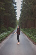 © Fauren - Brunette aged 20-25 in black leggings and a plaid shirt prances and dances on a forest path in a forest setting. The joy of movement and fresh air. Forest Fairy