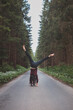 © Fauren - Acrobatic woman in black leggings and plaid shirt performs a cartwheel on a forest path in the middle of a deep forest. Coordination and agility training