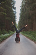 © Fauren - Acrobatic woman in black leggings and plaid shirt performs a cartwheel on a forest path in the middle of a deep forest. Coordination and agility training