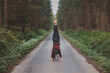 © Fauren - Acrobatic woman in black leggings and plaid shirt performs a cartwheel on a forest path in the middle of a deep forest. Coordination and agility training