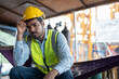 © Supachai - Asian man worker feeling tired while sitting at construction site.