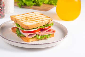 Close-up of two sandwiches with bacon, salami, prosciutto and fresh vegetables on rustic wooden cutting board. Club sandwich concept