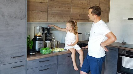 Wall Mural - Family with a young father and his little daughter preparing healthy juice or smoothie with fresh fruit in home kitchen