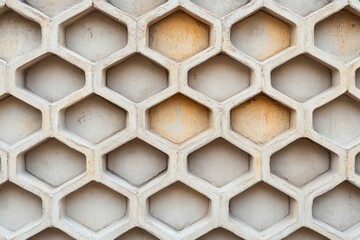 Wall Mural - Close-up view of a textured concrete wall featuring a honeycomb pattern, showcasing unique geometric shapes and color variations.