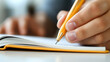 © nitnicha - Close-up of a person writing in a notebook with a yellow pen, showcasing creativity and organization in a comfortable setting.