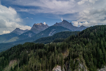 Majestic mountain range with lush forests under a cloudy sky in the Dolomites during late afternoon light