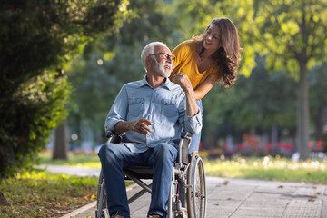 woman pushing man in wheelchair in park