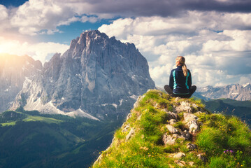 Wall Mural - sitting girl on the peak with yellow flowers and green grass in beautiful alpine mountain valley at 