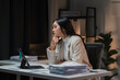 © Kritdanai - Late Night Contemplation: A young Asian businesswoman ponders a challenge at her desk, illuminated by the warm glow of her laptop in the quiet solitude of her home office.