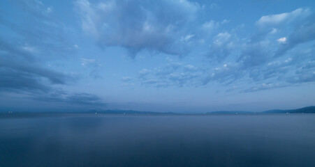 Wall Mural - beautiful sunrise with dramatic clouds over the lake and mountains.