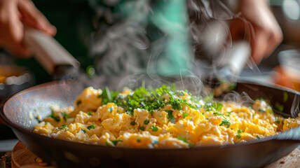 Scrambled eggs with fresh herbs cooking in skillet.