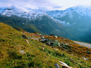 Wall Mural - mountainous landscape with verdant mountain slope in front of bare snow-capped mountain peaks in aut