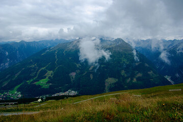 Wall Mural - view of an amazing mountain landscape with a village in the valley on a hazy day with gray clouds an