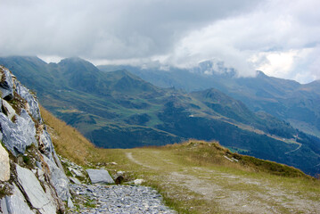 Wall Mural - view of an amazing mountain landscape with a stony path on a hazy day with gray clouds and fog over 