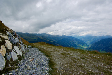 Wall Mural - view of an amazing mountain landscape with a stony path on a hazy day with gray clouds and fog over 