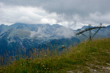 Wall Mural - view of an amazing mountain landscape with a gondola lift on a hazy day with gray clouds and fog ove