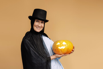 Wall Mural - Happy senior woman holding a jack o'lantern celebrating halloween