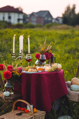 Fall mood, romantic date outdoors in the garden, candlelight dinner for a couple. Private wedding for two. Pumpkin countryside decor, red dahlia, cheese plate, grapes. Gourmet food, elegant setting