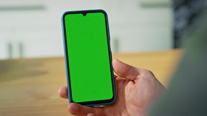 Hand holding green screen smartphone at home closeup. Unrecognizable businessman