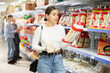 © JackF - Positive young girl shopping in Asian food store, choosing traditional noodles for dinner..