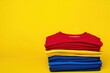 © ProArtStock - Colorful t-shirts against a yellow background with copy space