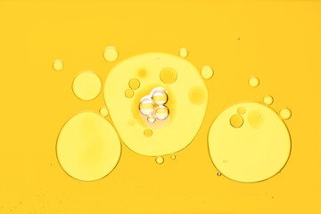 Poster - Sample of cosmetic oil on yellow background, macro view