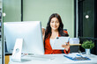 © M+Isolation+Photo - young Asian businesswoman in a formal suit works at her desk in a modern glass office, consulting on LGBTQ-inclusive strategies across various business domains, including HR, IT, and marketing.