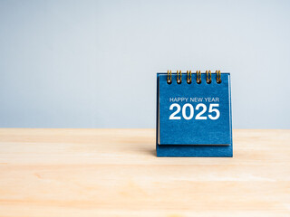 Wall Mural - Happy new year 2025, text and numbers on blue small desk calendar cover standing on wood table and white background with copy space, minimal style. Business plan agenda, success and goal concept.