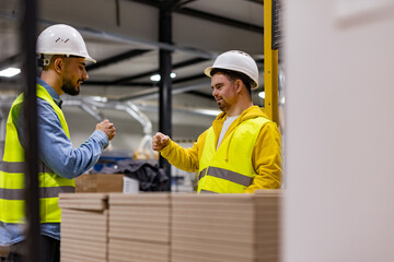 Wall Mural - Young man with Down syndrome working in modern factory, fist bump with colleague. Concept of workers with disabilities, support in workplace.