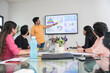© GAJENDRRA BHATI  - young indian man presents business financial data with charts and graphs on wall tv in the meeting room to colleagues for a start-up project. sales, analysis and strategy concepts.
