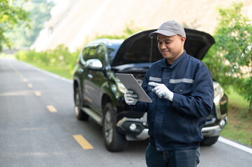 Asian male professional auto mechanic doing onsite service checking broken engine. Inspect the damage according to the list to replace parts and maintain the car on-site. emergency assistance service