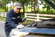 © PhugunStock - Asian male professional auto mechanic doing onsite service Open the bonnet to check for a broken engine. Inspect the listed damage and maintain emergency assistance services.