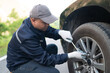 © PhugunStock - Asian male professional auto mechanic doing onsite service using tire changer wrench equipment. Inspect the damage according to the list and maintain the car on-site, emergency assistance service.