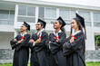 © Kawee - Group of successful diverse graduated students standing outside campus.