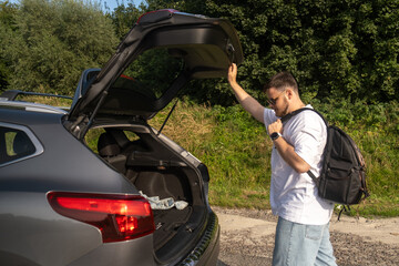 Man with Backpack at Open Car Trunk