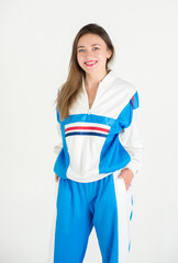 Young girl in a tracksuit emotionally poses on a white background standing.