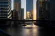 © yaqui_villegas - This image shows the sun setting, reflecting off the water in an urban financial district, with skyscrapers lit by the golden hour, creating a serene and reflective atmosphere.