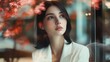 © fotofabrika - A young woman gazing thoughtfully through a glass window surrounded by autumn foliage in a cozy café