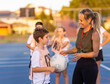 © Austockphoto - lady with whistle on lanyard coaching children's netball team