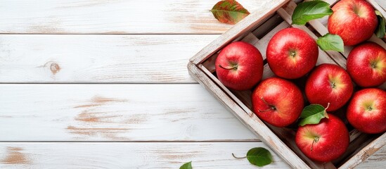 Poster - Red apples in a wooden box Organic red apples with leaves on a white wooden surface top view copyspace