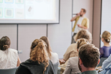 Wall Mural - Speaker engaging audience at business seminar, presenting information on screen in formal conference setting