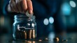 © arhendrix - Hand placing coin in jar labeled 'Retirement Fund', exemplifying savings, financial planning, and future investments. Blurry blue background.