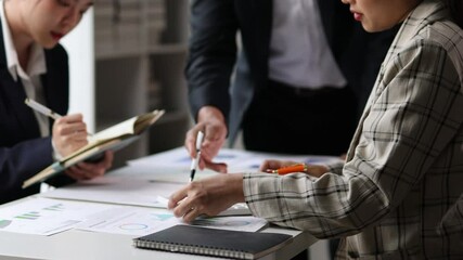 Wall Mural - Financial analysts strategizing on charts and data during a meeting. Financial analysts discuss charts and graphs, using calculator to analyze data during a business meeting.