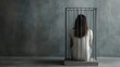 © Janyawatt - A somber scene of a woman sitting alone in a small cage against a dark, textured background, symbolizing feelings of entrapment, isolation, and despair