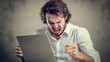 © Felippe Lopes - Frustrated man yells at his computer, showing anger and stress.