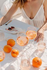 A woman is sitting at a table with a glass of wine and a glass of orange juice