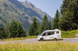 © Kirill Gorlov - Scenic view big modern white family rv camper van vehicle drive Europe highway road alpine pass mountain sunny summer day. Rving motorhome lifestyle travel adventure tourism trip Alps journey concept
