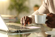 © PheelingsMedia - Black man hands using laptop and holding coffee cup